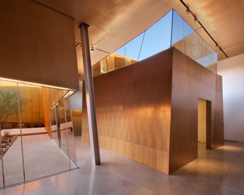 Modern architectural space featuring wooden walls, glass elements, and a bright, open design with natural light.