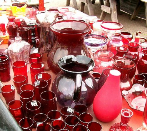 A collection of various red glassware, including pitchers, vases, and cups, displayed on a table.