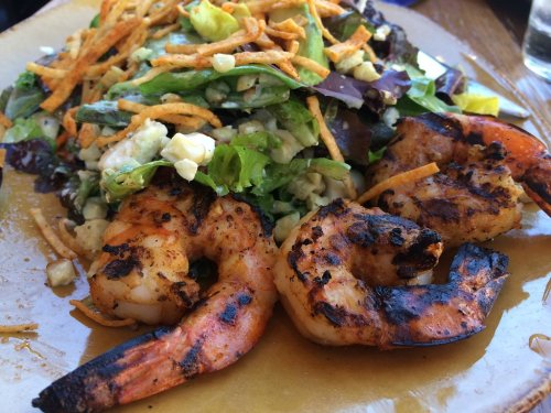 Grilled shrimp served on a bed of mixed greens, topped with tortilla strips and avocado.