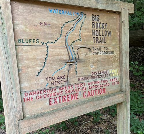 Wooden trail sign with a map of Big Rocky Hollow Trail, indicating locations, distances, and caution warnings.