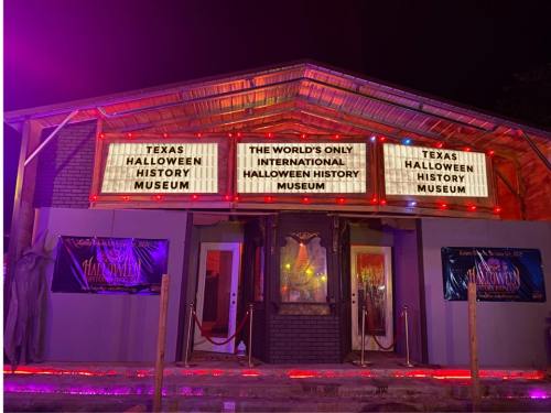 Exterior of the Texas Halloween History Museum, featuring bright lights and signs promoting its unique Halloween exhibits.