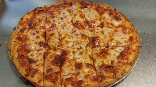 A freshly baked pizza with melted cheese, sliced into equal pieces, resting on a silver surface.