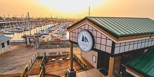 A marina at sunset with boats docked, featuring a building labeled "Marty's Landing" in the foreground.
