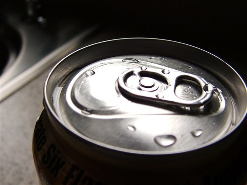 Close-up of a soda can top with droplets of water, set against a blurred background.