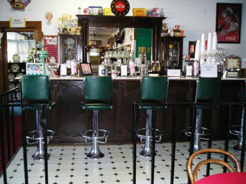 A vintage diner interior featuring a bar with green stools, retro decor, and a checkered floor.