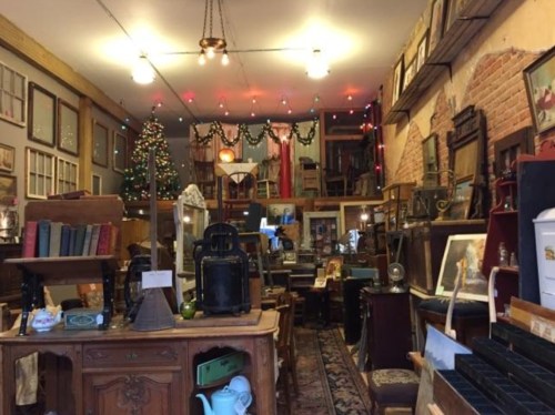 A cozy antique shop filled with vintage items, furniture, and holiday decorations, creating a warm, nostalgic atmosphere.