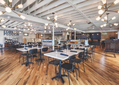 Modern restaurant interior with wooden floors, stylish lighting, and neatly arranged tables.