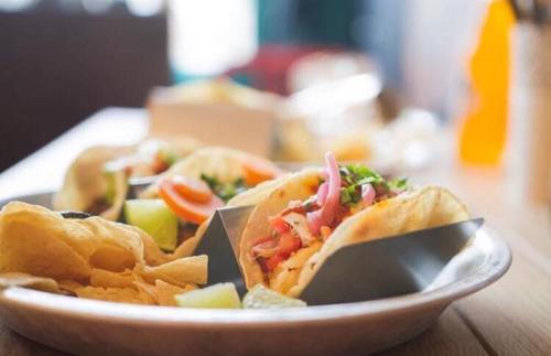 A plate of colorful tacos with fresh toppings, served alongside crispy tortilla chips.