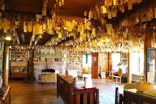 A cozy room filled with wooden beams, walls adorned with hanging tags, and a warm seating area.