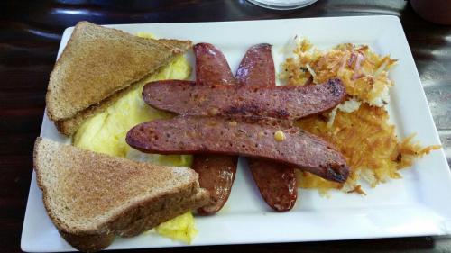A plate of breakfast featuring two slices of toast, three sausage links, an omelet, and hash browns.