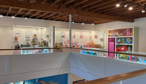 A brightly lit gallery showcasing colorful toys and collectibles in glass display cases.
