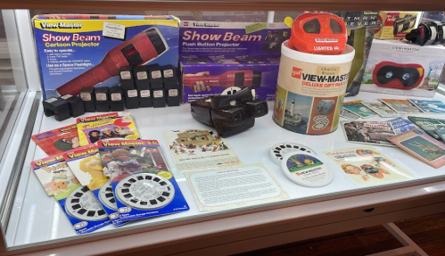 Display of vintage View-Master items, including projectors, reels, and promotional materials in a glass case.