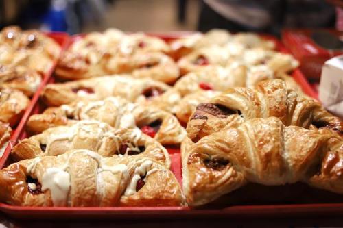 A tray of assorted pastries, including croissants and danishes, with various fillings, displayed in a bakery setting.
