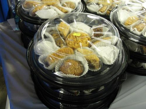 A stack of clear plastic containers filled with assorted pastries, each in paper liners, on a table.