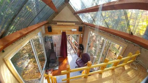 Cozy interior of a modern cabin with large windows, wooden accents, and a staircase leading to a lower level.