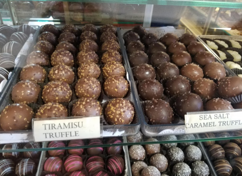 A display of assorted truffles, including tiramisu and sea salt caramel, with various toppings and textures.