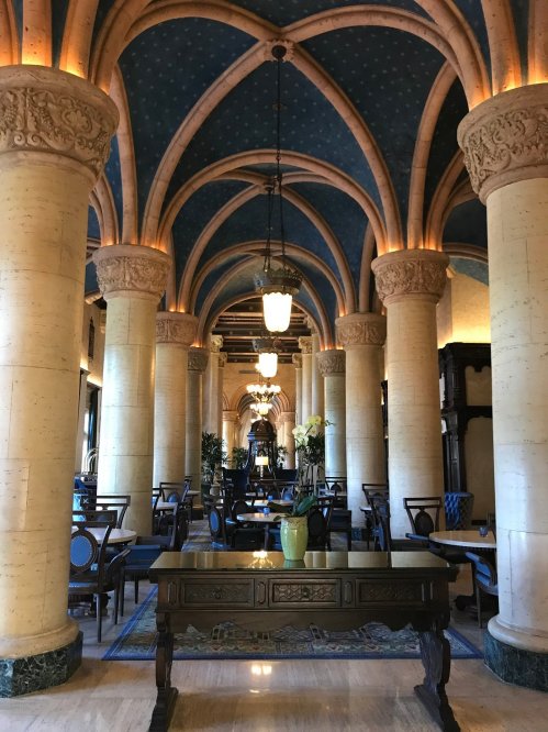 Elegant interior of a grand hall featuring arched ceilings, decorative columns, and stylish dining furniture.