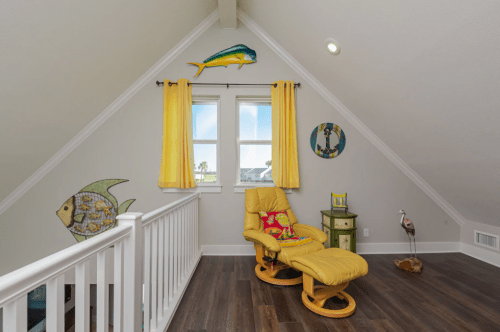 Bright attic space with yellow curtains, a cozy yellow chair, and playful fish decor on the walls.