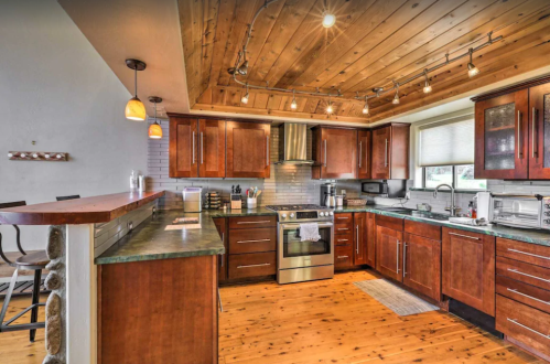 Modern kitchen with wooden cabinets, stainless steel appliances, and a cozy, rustic design featuring a wooden ceiling.