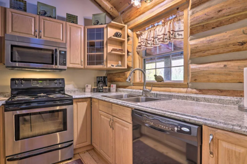 Cozy log cabin kitchen featuring wooden cabinets, stainless steel appliances, and a granite countertop.