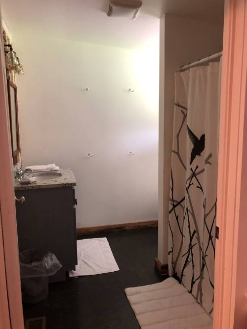 A bathroom with a shower curtain, a sink with a countertop, and towels on the floor.