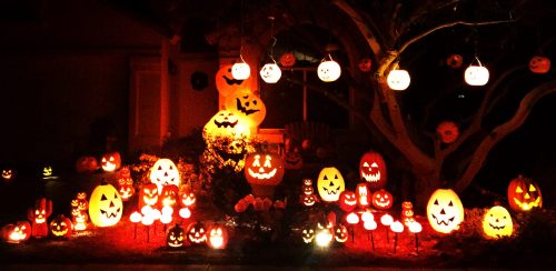 A spooky Halloween display featuring numerous carved pumpkins and glowing lanterns in a dark, festive setting.