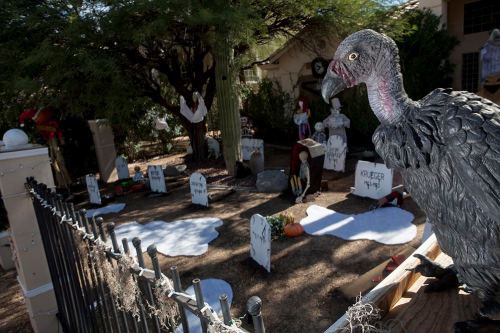 A spooky Halloween scene featuring a vulture statue near a graveyard with tombstones and eerie decorations.