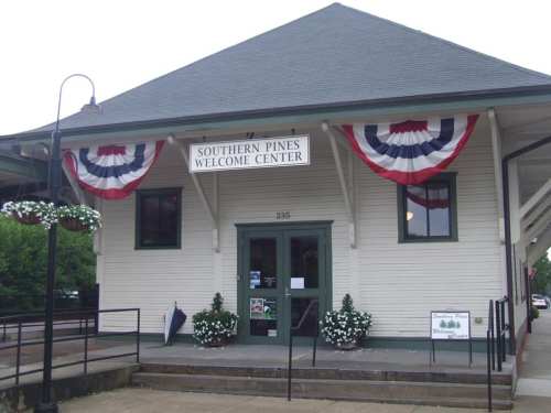 Southern Pines Welcome Center building with patriotic bunting and flower planters at the entrance.