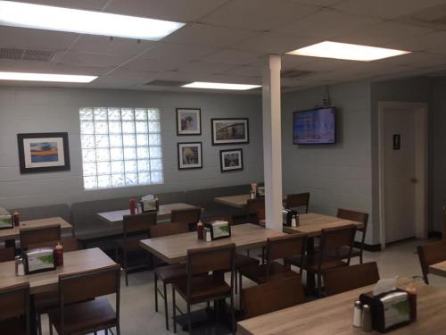 A cozy restaurant interior with wooden tables, chairs, framed photos on the walls, and a TV in the corner.