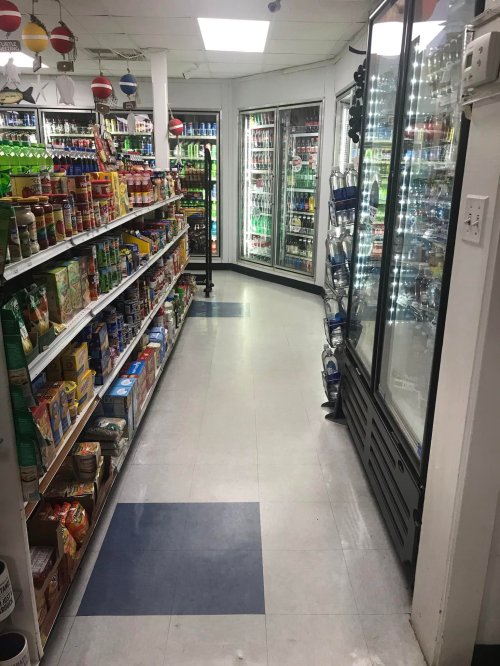 A grocery store aisle with shelves of food items on one side and a refrigerated section on the other.