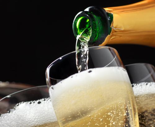 A bottle of champagne is being poured into a glass, creating bubbles and a frothy top.