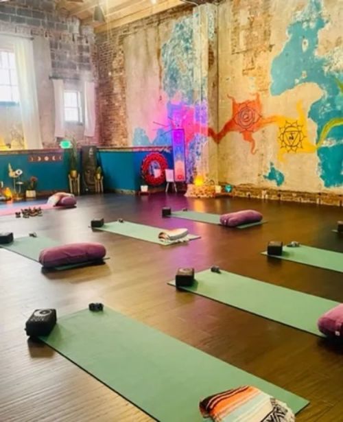 A serene yoga studio with mats, cushions, and colorful wall art, creating a calming atmosphere for practice.
