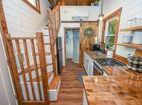 Cozy kitchen with wooden accents, stairs, and modern appliances in a bright, compact space.