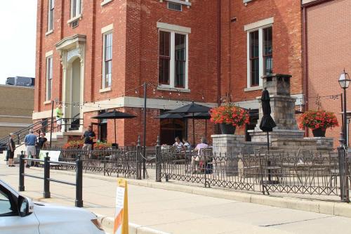 Outdoor dining area of a brick building, featuring tables, umbrellas, and flower planters along a sidewalk.