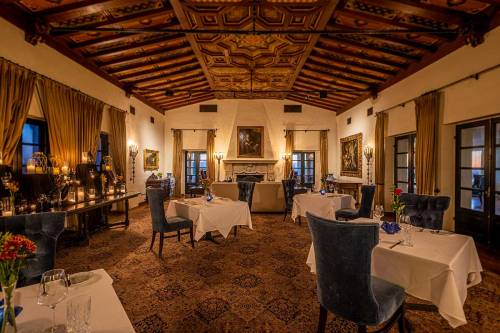 Elegant restaurant interior with ornate ceiling, tables set for dining, and warm lighting creating a cozy atmosphere.