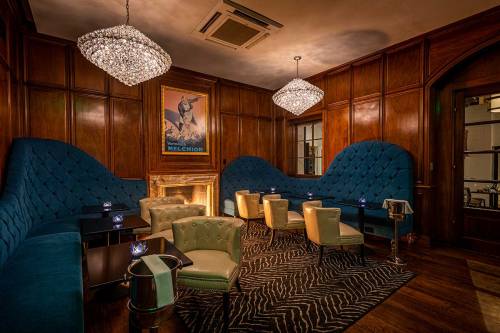 Cozy lounge with blue tufted seating, elegant chandeliers, and a warm fireplace, featuring a stylish zebra-patterned rug.