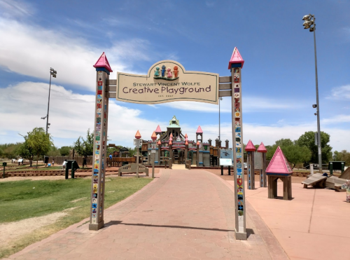 Entrance to Stewart Vincent Wolfe Creative Playground, featuring colorful structures and a blue sky.