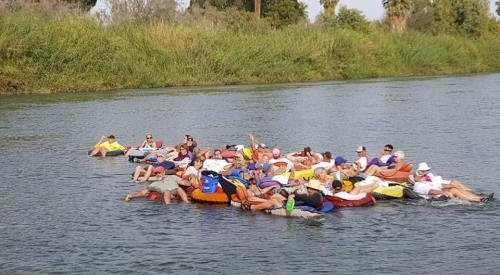 A group of people floating on colorful inner tubes in a river, enjoying a sunny day outdoors.