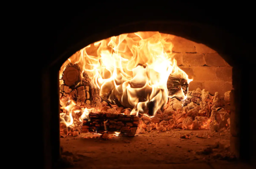 Flames and glowing embers inside a brick fireplace, creating a warm and inviting atmosphere.