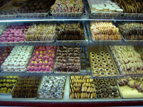 A display case filled with a variety of colorful cookies and pastries, including sprinkles, chocolate, and frosted treats.