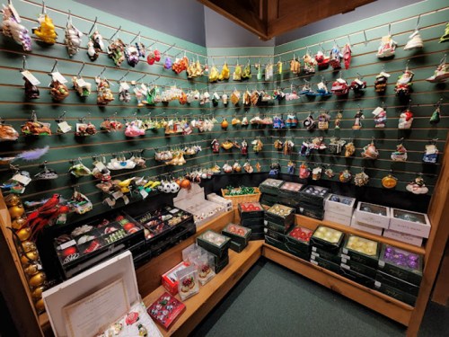 A display of colorful ornaments hanging on a wall, with various shapes and sizes arranged on shelves below.