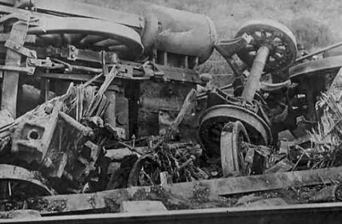 A close-up of a derailed train, showing twisted metal and debris scattered on the ground.
