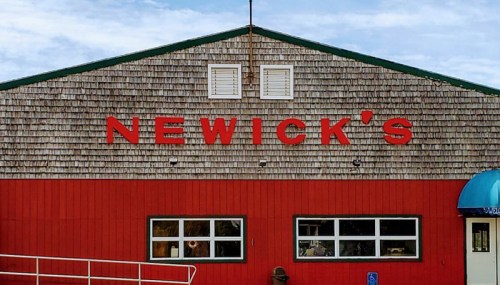 Signage of Newick's restaurant on a wooden building with a red lower section and green roof.