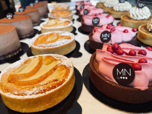 A variety of beautifully decorated cakes and tarts displayed on a table, featuring different flavors and toppings.