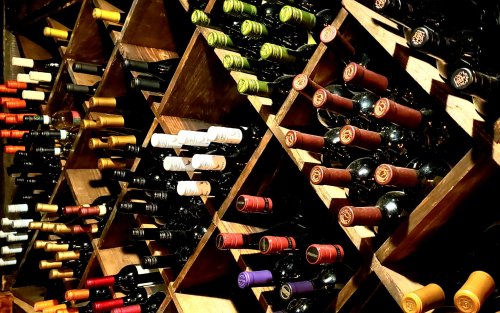 A wooden wine rack filled with various bottles of wine, showcasing different colors and labels.