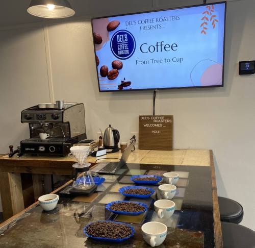 A coffee roastery setup with brewing equipment, coffee beans, and a screen displaying "Coffee: From Tree to Cup."