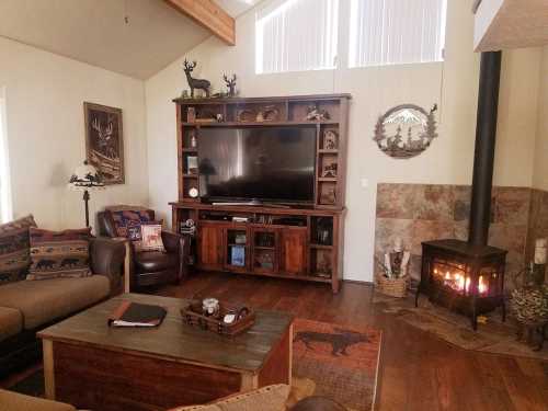 Cozy living room with a wooden TV stand, comfortable seating, and a stone fireplace, decorated with rustic accents.