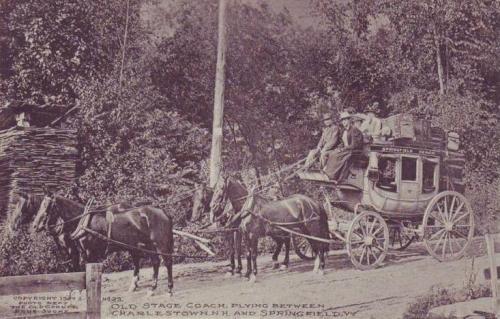 An old stagecoach with passengers, pulled by horses, on a dirt road surrounded by trees.
