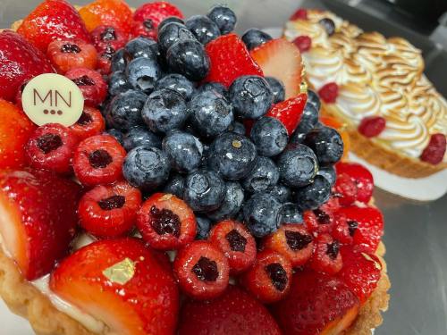 Two colorful fruit tarts topped with strawberries, blueberries, and raspberries, with a decorative chocolate piece.