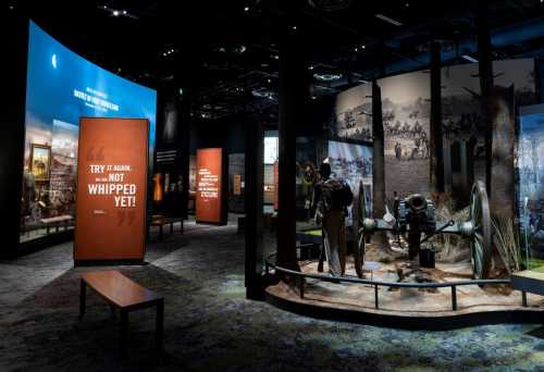 Exhibit space featuring historical displays, banners, and artifacts in a dimly lit museum setting.